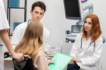 Fototapeta premium A nurse brought the teen in a wheelchair to the doctor's room. GP. The redheaded intern
