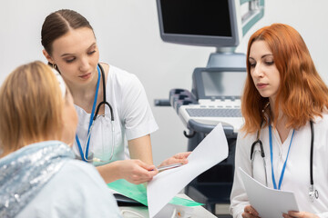The doctor explains to the patient one by one the various test results. A 50-year-old woman in a...