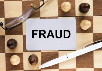 Business card with text Fraud on a chess board with pen and eyeglasses