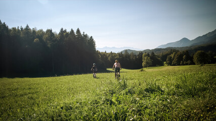 Fototapeta premium Two females on mountain bikes talking and looking at beautiful green nature.