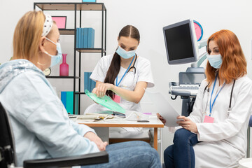 A doctor takes out her patient's medical records. A 50-year-old woman in a wheelchair in the...