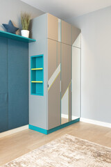 A gray wardrobe with niche shelves, with a geometric pattern on the facade, with mirrors, in a teenager's room. Concept of modern interior details in an apartment or house. Vertical