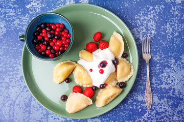Pierogi stuffed with curd served with sour cream, strawberries and currants.