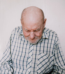 a large portrait of an old man on a light background with deep wrinkles, age spots.