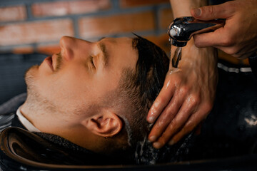 A man in a barbershop receives a haircut service, after a haircut, washing is ready with shampoo and special care products, personal care