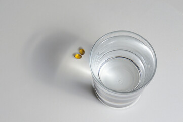 a glass beaker and two yellow tablets with vitamins. close-up.