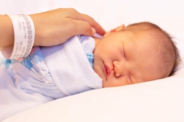 A mother putting her newborn baby to sleep at the hospital. Childbirth and infancy.