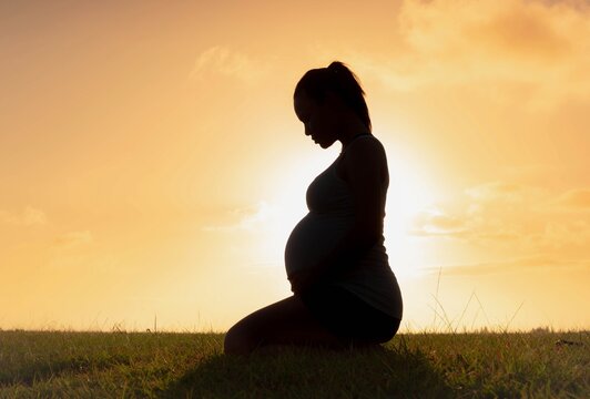 A pregnant woman sitting outdoor during sunset beautiful outdoor.. Maternity.