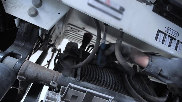 Mechanic uses hand wrench tool to install a new part in place on a truck during an annual maintenance service at a service station