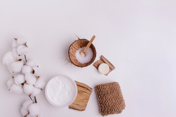 Cosmetic sea salt in coconut rind and cotton flowers  with coconut cream on a white background