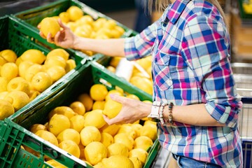 Woman shopping fruits food at store. Choosing lemon.