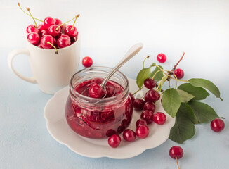 Cherry jam with fresh cherries on a blue background.