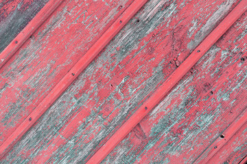 Background from old diagonal boards with peeled red paint with nails