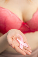 In her right hand extended in front of her, the girl holds a pink ribbon - Symbol of the fight against breast cancer.