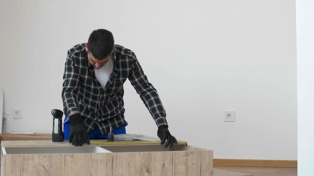 Carpenter measuring shelves that are parts of new kitchen with meter.