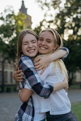 Portrait of smiling best friends embracing each other on the street, having fun. Positive...