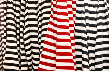 Sale of clothing in the store. Texture of striped T-shirts with red and black stripes