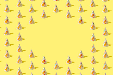 Creative birthday pattern made of birthday hats on yellow background. Minimal party concept with copy space.