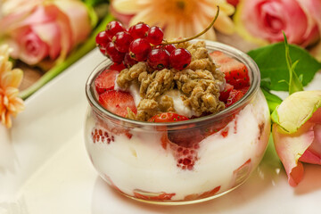 Close-up of a healthy yogurt with muesli and fruits in a lovely arrangement with flowers 