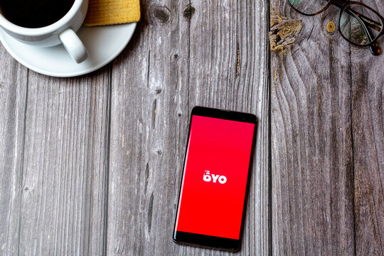 04-13-2021 Portsmouth, hampshire, UK A Mobile phone or cell phone laid on a wooden table showing the oyo app on screen