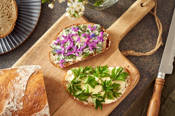 Two slices of bread with wild edible spring plants - young goutweed leaves, purple dead-nettle and...