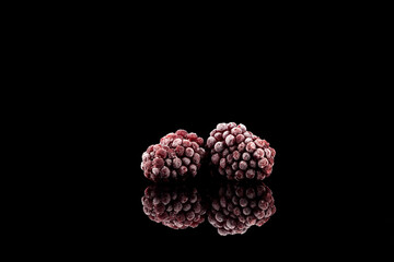 Frozen blackberry on dark background with reflection. Close-up, copy space. Concept - Reserve vitamins for winter