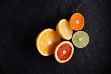 Fresh juicy ripe citrus fruits (Lemon, lime, red orange, mandarin) on dark stone background