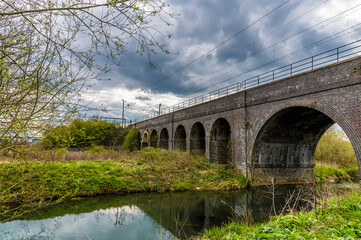 Fototapeta na wymiar A view across the River Nene towards the Far Cotton Railway viaduct in Northampton, UK on a bright Spring day