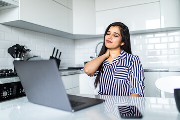 Upset indian woman working from home office. Unhappy freelancer using laptop and the Internet. Workplace in cozy kitchen.