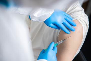 A doctor dressed in a protective suit vaccinates a patient against coronavirus.