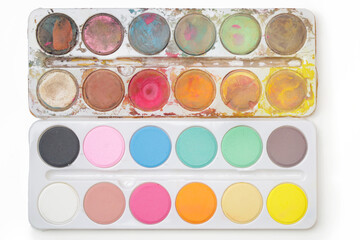 Old and new watercolor paints palette next to each other.