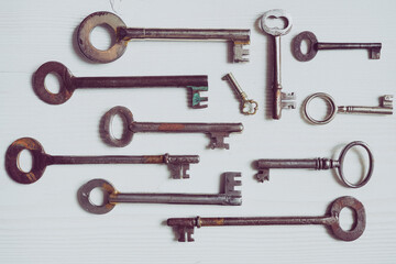 Different old fashioned keys on a white table - 427755077