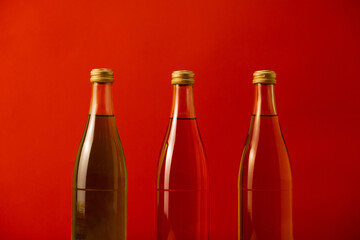 Three glass multi-colored bottles with a drink on a red background