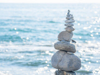 Pyramid of pebbles and stones on beach. Sunny day at seaside. Leisure on ocean coast.