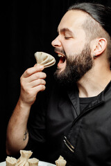 The bearded man is emotionally eating khinkali. The national Georgian dish khinkali. Concept of advertising photo of khinkali