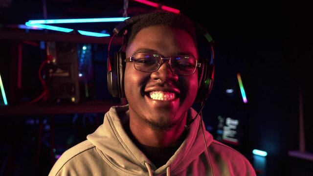A close-up portrait of a cute black student wearing glasses and headphones, smiling at the camera