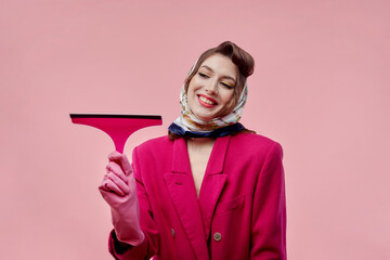 A young beautiful woman holds a scraper, a window cleaning tool. Bright makeup. Pin-up style.