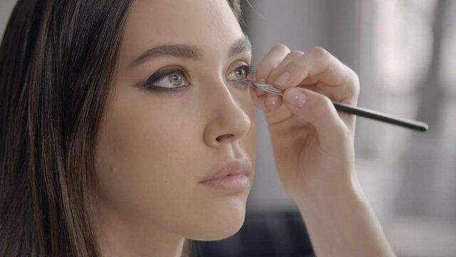 Woman applies make-up on a model in a studio. Close-up of a caucasian girl preparing for a catwalk fashion show. High quality 4k footage