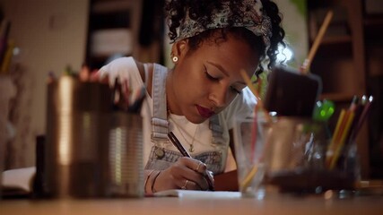 Artist drawing with a pencil and a sheet of paper. Creative African American woman drawing.
