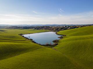 Impressive landscape with a lake. Crete Senesi, Tuscany, Italy.  Aerial view, drone shot.