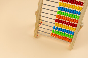 Wooden abacus with beads on beige background. Back to school, games for kindergarten, preschool education.