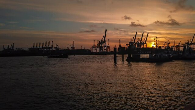 Sunset timelapse in Hamburg (Germany). Harbour sunset with boats and cranes.