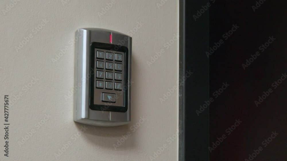 Poster a man's holds a security card-faub up to a numeric keypad, which allows access to a locked door insi