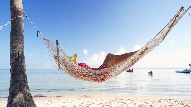 Girl relaxing in a hammock on tropical island beach. Summer vacation.
