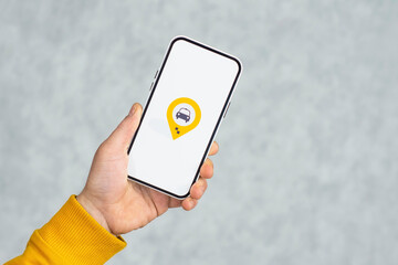Phone display with Taxi icon on light background. Man holds a mockup smartphone in his hand...