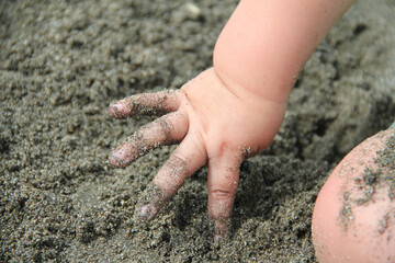 baby toddler hand in the sand getting dirty, playing outside at the beach