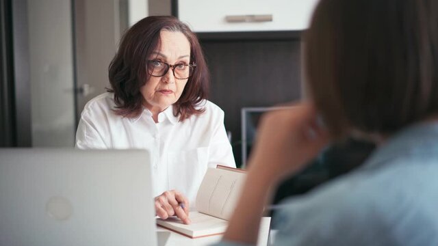 Middle-aged old businesswoman manager mentor speaking to a client offering insurance banking services deal teaching intern or convincing customer.