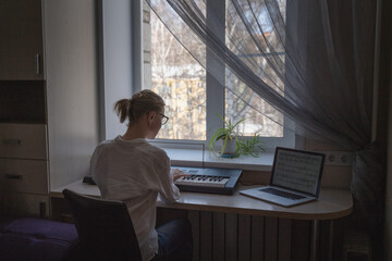 Beautiful young blonde woman teacher playing piano giving online lessons from home