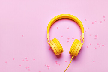 Yellow headphones and confetti on pink background. Minimal Music concept, flat lay, copy space