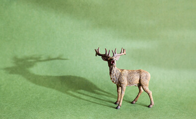 Deer figurine on a green background. Realistic toy, replica of a wild animal